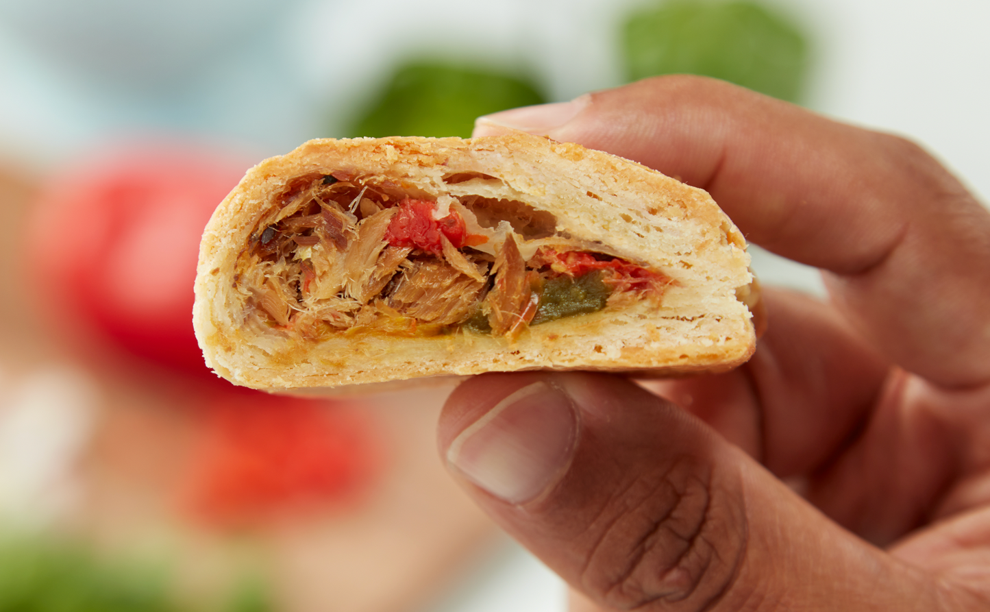 Hand holding a half-eaten pastry with visible filling against a blurred background