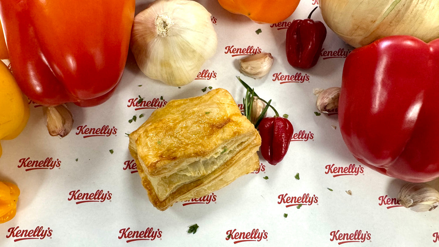 Baked pastry on a surface with red peppers and garlic, branded 'Kenellys'.